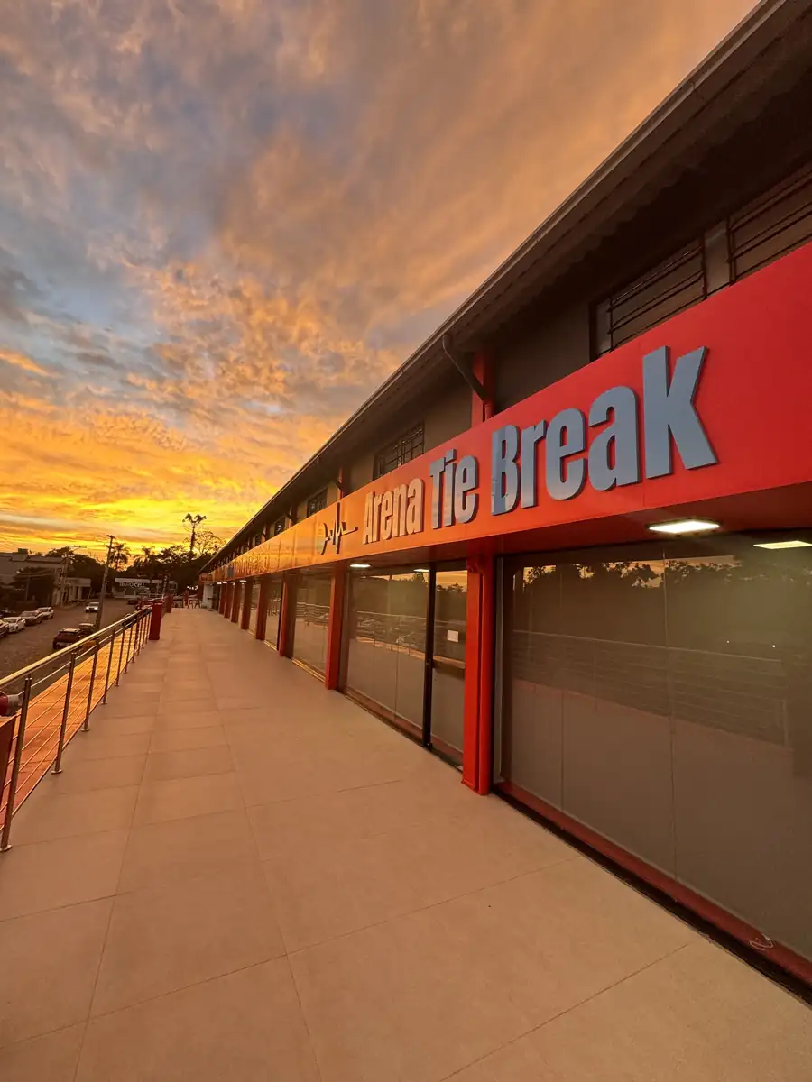 Fachada vermelha com o letreiro Arena Tie Break ao pôr do sol